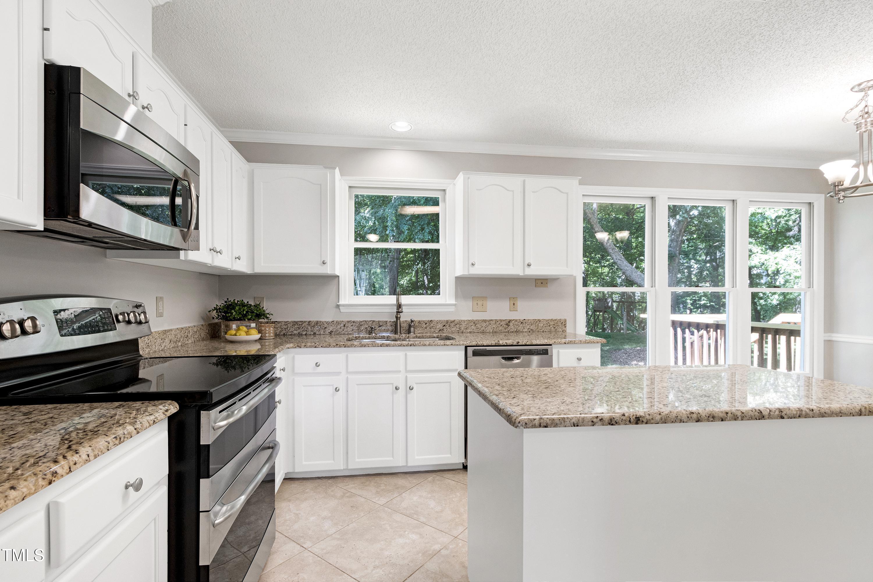 300 Silvercliff Trail Cary, NC 27513 - Photo 2 of 27 a kitchen with granite countertop a sink a stove a microwave a counter top space and cabinets