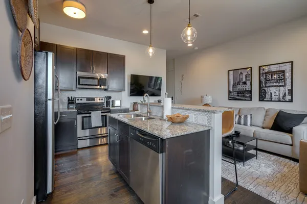 a kitchen with stainless steel appliances granite countertop a refrigerator a sink dishwasher a stove and a refrigerator with wooden floor