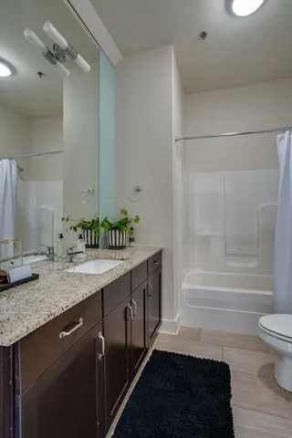 a bathroom with a granite countertop sink and a toilet