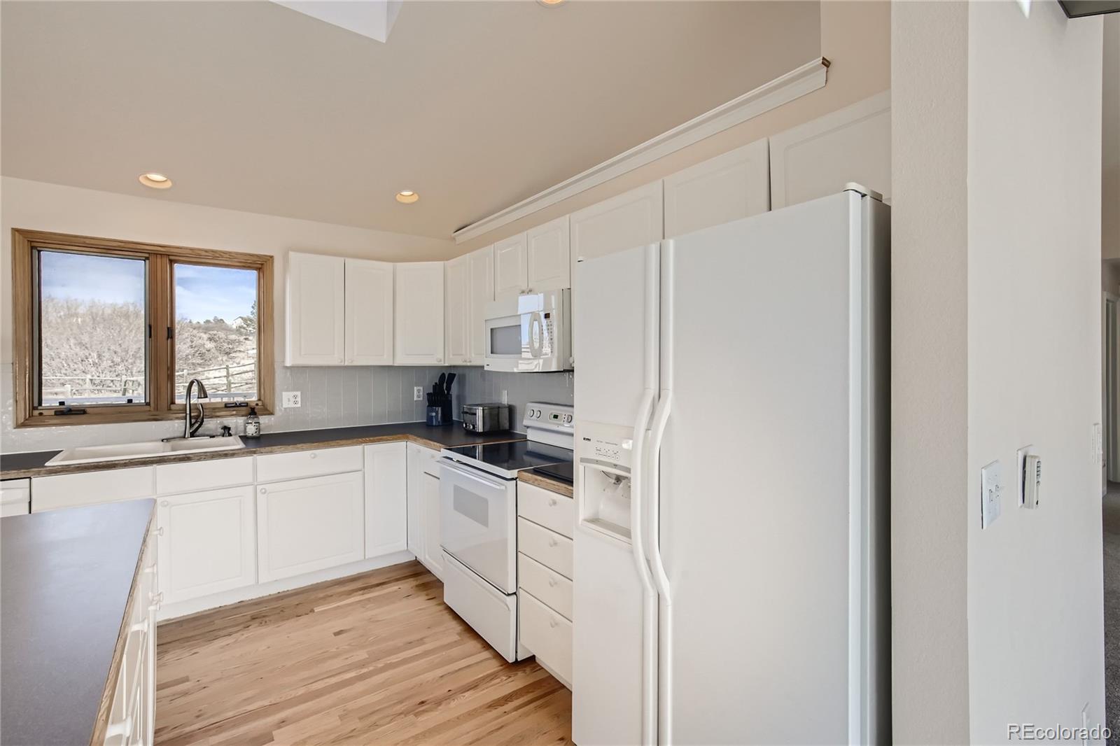 3961 Bear Canyon Circle Sedalia, CO 80135 - Photo 8 of 40 a kitchen with white cabinets and white appliances
