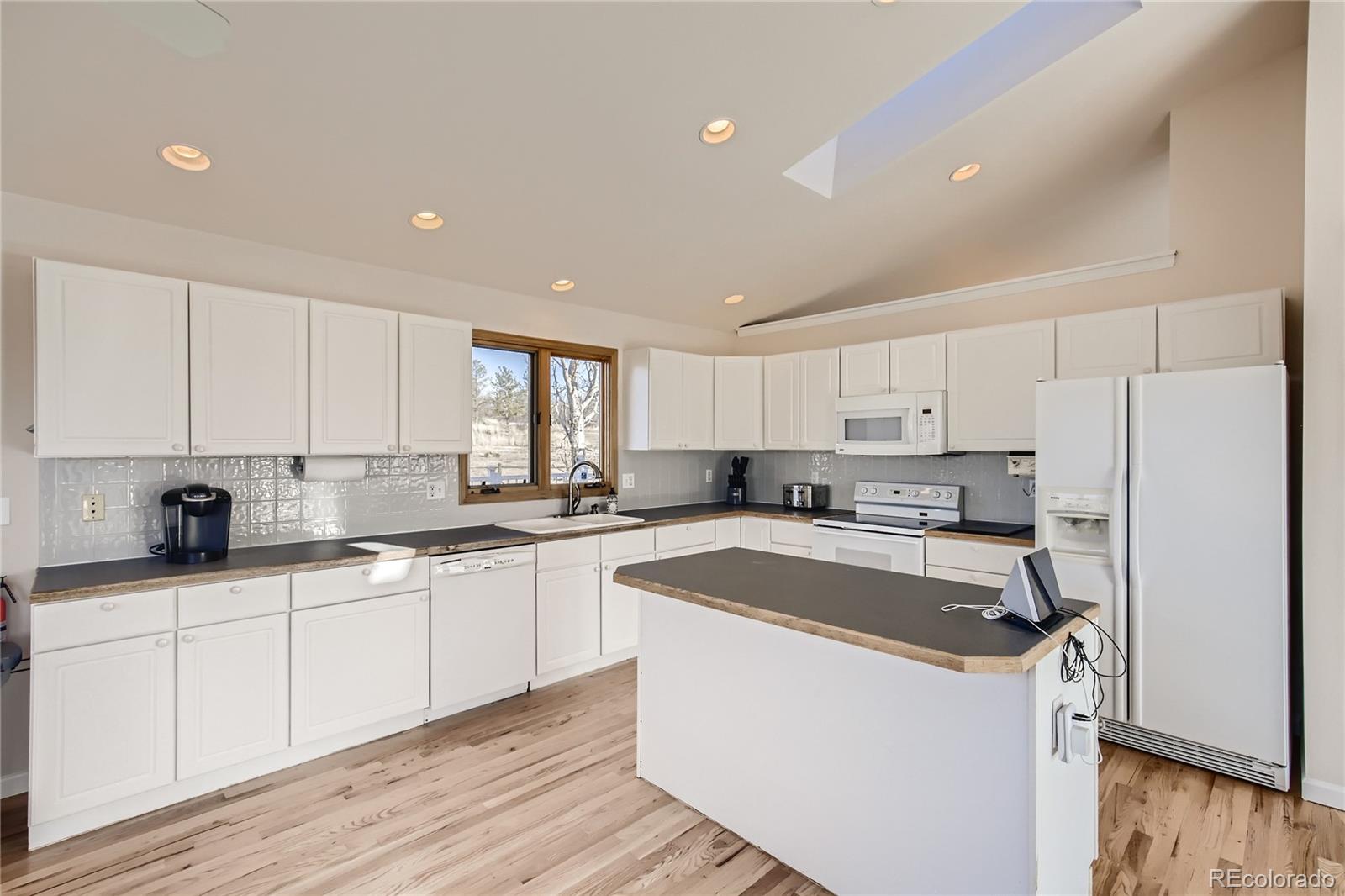 3961 Bear Canyon Circle Sedalia, CO 80135 - Photo 10 of 40 a kitchen with a sink a stove a refrigerator and white cabinets