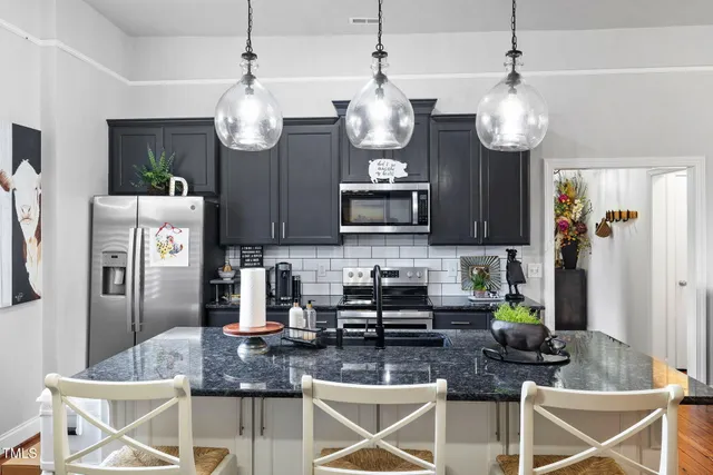 a kitchen with stainless steel appliances granite countertop a stove a kitchen island a refrigerator and fireplace