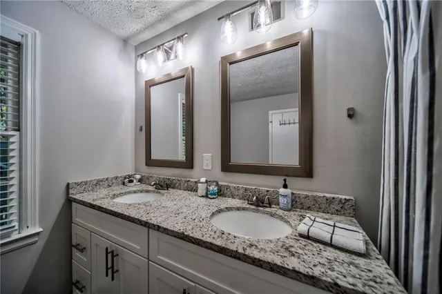 a en suite bathroom with a granite countertop double vanity sink and a mirror