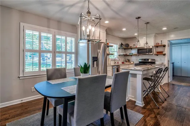 a kitchen with stainless steel appliances a dining table chairs and refrigerator