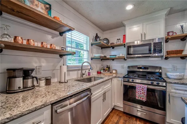 a kitchen with granite countertop a sink cabinets and stainless steel appliances