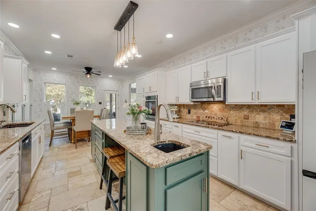 a kitchen with kitchen island granite countertop a sink a stove and cabinets