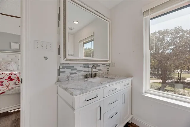 a bathroom with a granite countertop sink mirror and a window