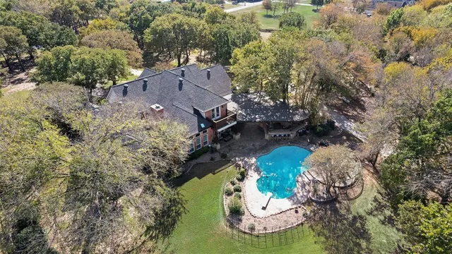 aerial view of a house with a yard and large trees