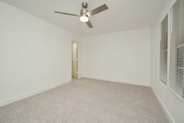 an empty room with a ceiling fan and a window