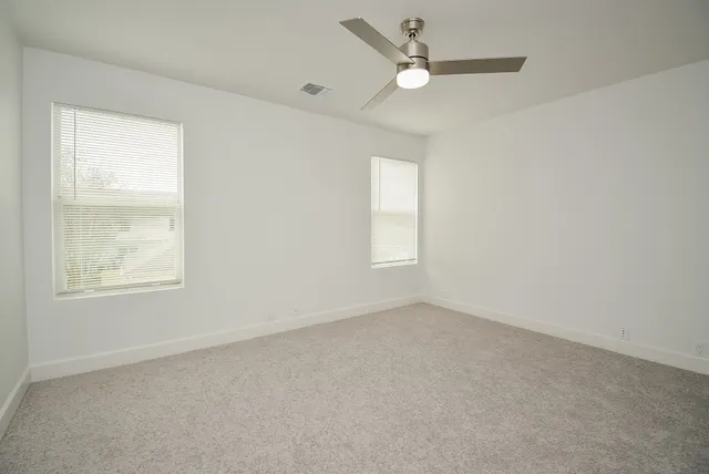 an empty room with a window and a fan