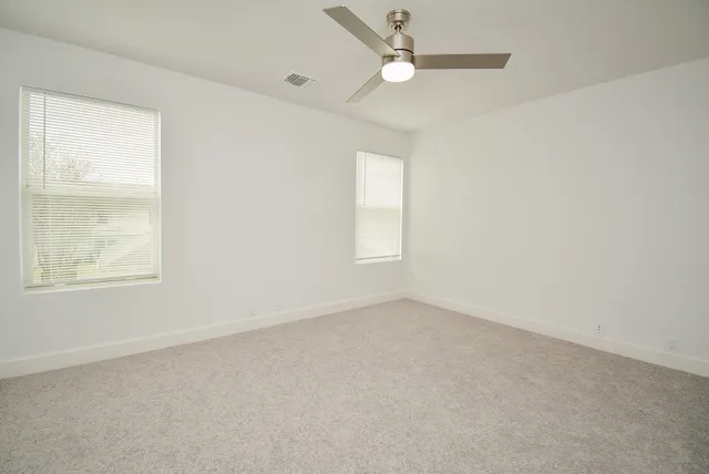 an empty room with a window and ceiling fan