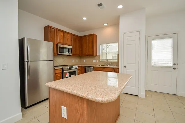 a kitchen with stainless steel appliances granite countertop a refrigerator a stove a sink and a refrigerator