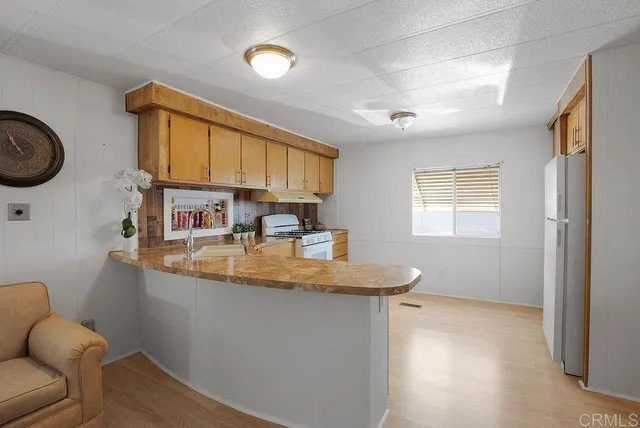 a kitchen with stainless steel appliances granite countertop a sink a stove and a refrigerator with wooden floor