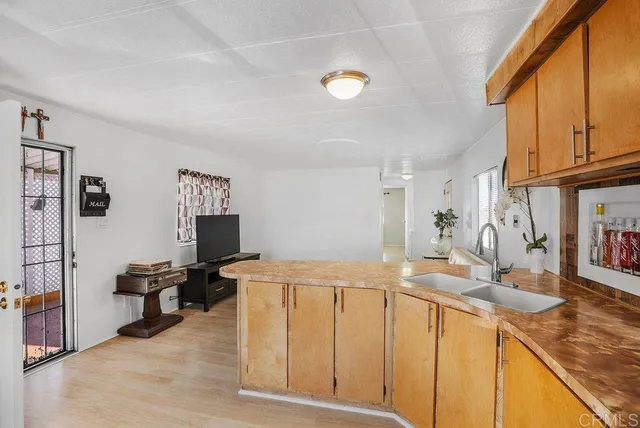 a living room with stainless steel appliances kitchen island granite countertop a sink and cabinets