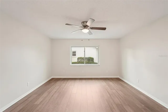 an empty room with wooden floor and ceiling fan