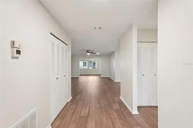 a view of empty room with wooden floor and fan
