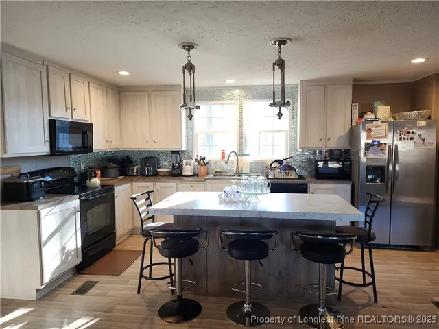 a kitchen with stainless steel appliances granite countertop a sink a stove a refrigerator cabinets and chairs