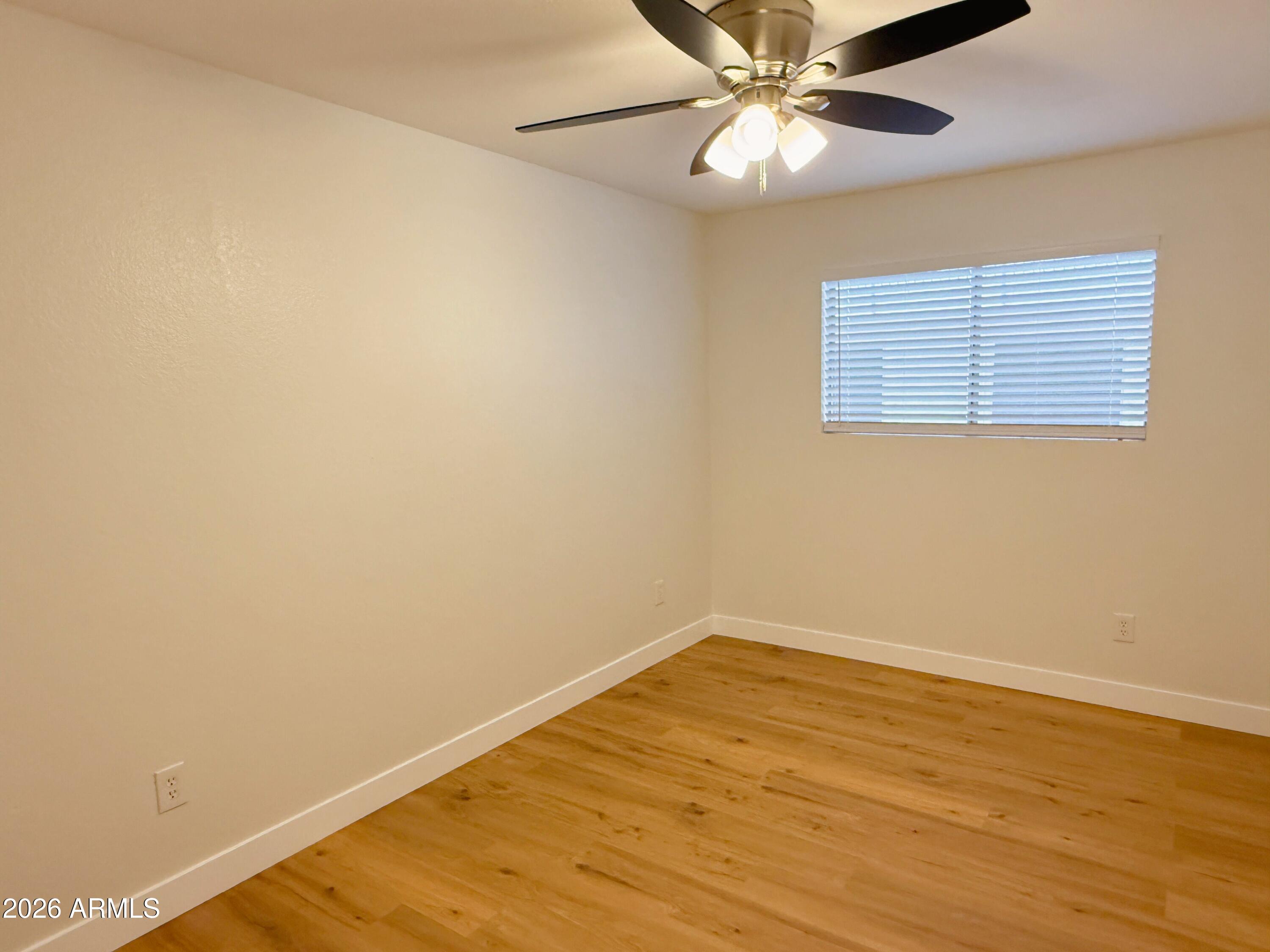 18202 North Cave Creek Road, Unit 148 Phoenix, AZ 85032 - Photo 13 of 19 a view of an empty room with wooden floor and a window