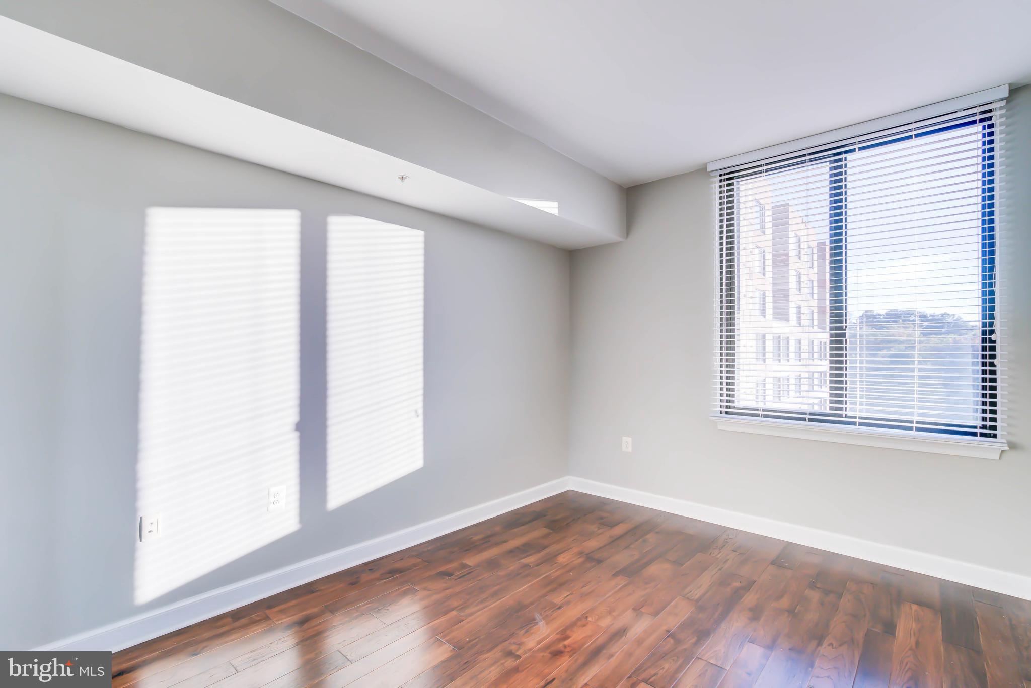 2451 Midtown Avenue, Unit 1327 Alexandria, VA 22303 - Photo 19 of 32 an empty room with wooden floor and windows