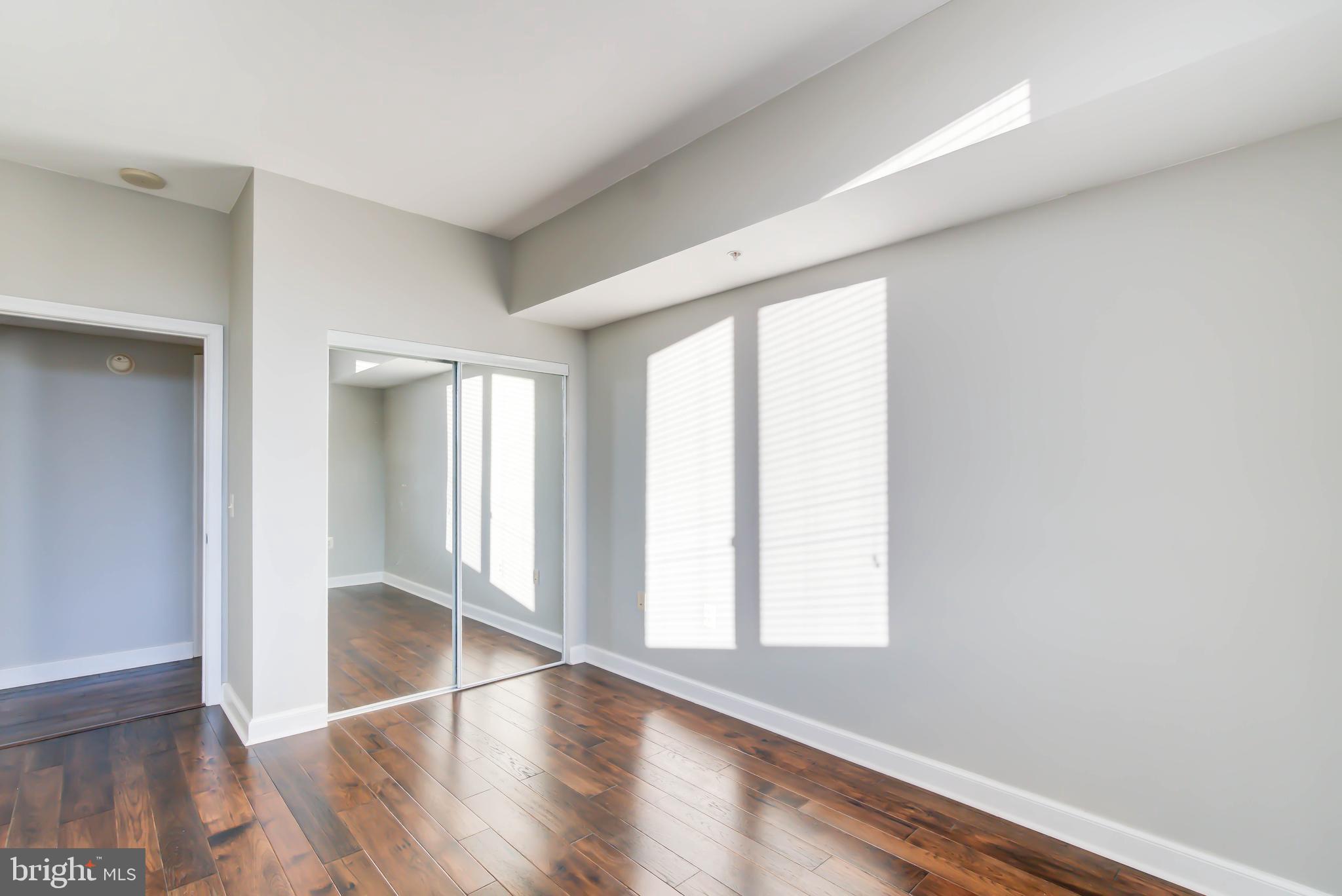 2451 Midtown Avenue, Unit 1327 Alexandria, VA 22303 - Photo 21 of 32 an empty room with wooden floor and windows