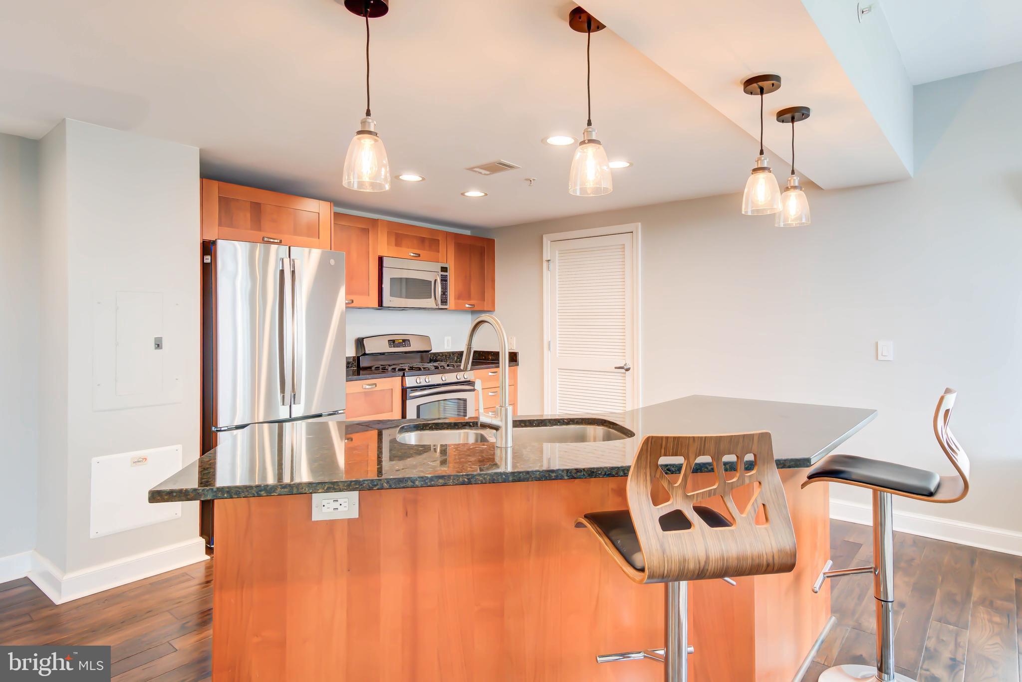 2451 Midtown Avenue, Unit 1327 Alexandria, VA 22303 - Photo 3 of 32 a kitchen with stainless steel appliances granite countertop a stove a refrigerator a sink dishwasher a dining table and chairs with wooden floor