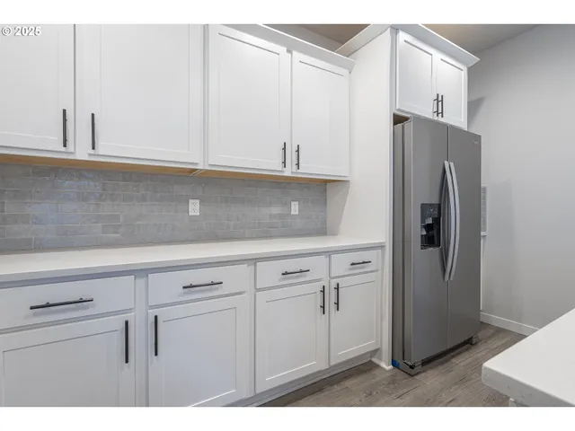 a kitchen with white cabinets and refrigerator