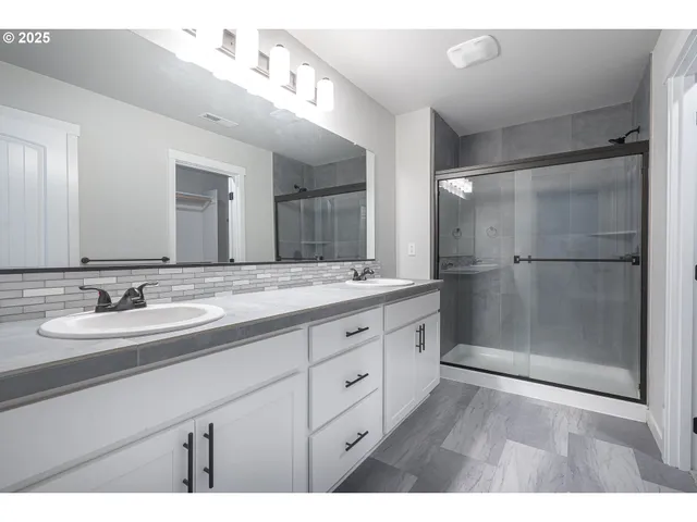 a bathroom with a double vanity sink mirror and shower