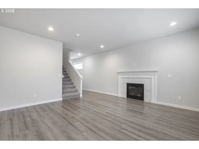 a view of an empty room with wooden floor and a fireplace