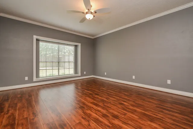 a view of an empty room with wooden floor and a window