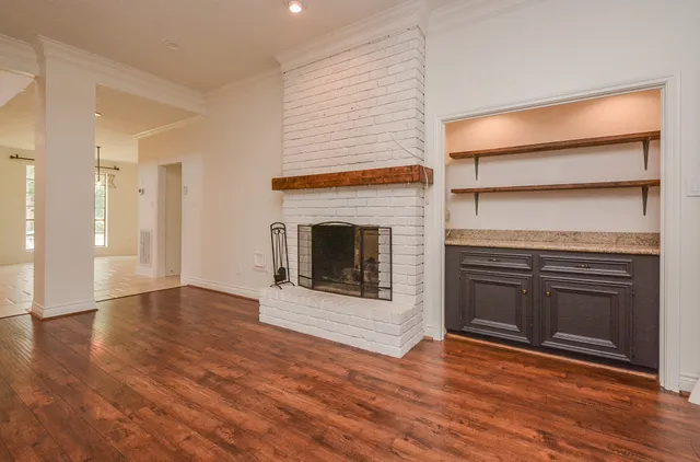 an empty room with wooden floor fireplace and windows