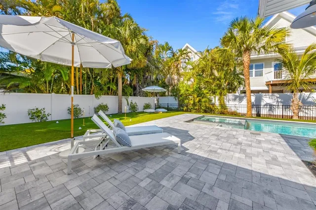 a view of a backyard with swimming pool and sitting area