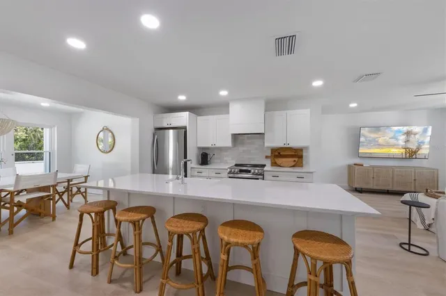 a large kitchen with stainless steel appliances granite countertop a stove a sink a dining table and chairs