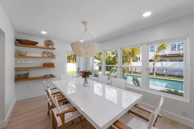 a view of a dining room and livingroom with furniture wooden floor a rug a painting and a chandelier