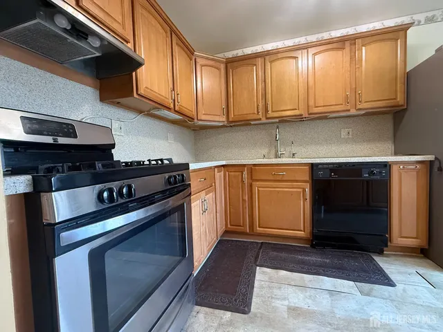 a kitchen with stainless steel appliances granite countertop a refrigerator a stove and a sink with wooden floor