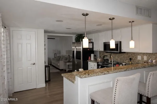 a kitchen with stainless steel appliances kitchen island granite countertop a sink a stove and a wooden floor