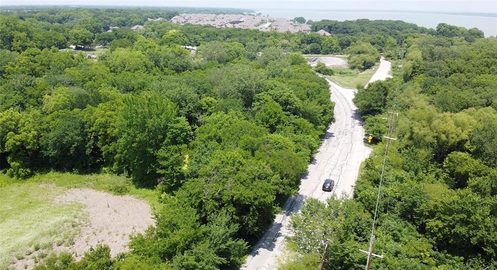8829 Dalrock Road Rowlett, TX 75089 - Photo 2 of 3 Expansive treed landscape featuring a paved road, a separate unpaved road, and distant water