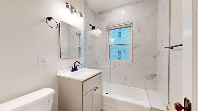 a bathroom with a sink a toilet a mirror a vanity and bathtub