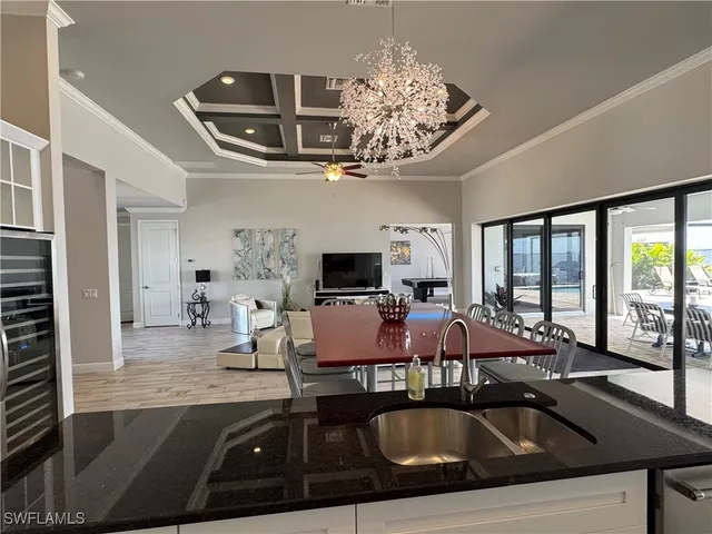 a view of a dining room with furniture a chandelier and large windows