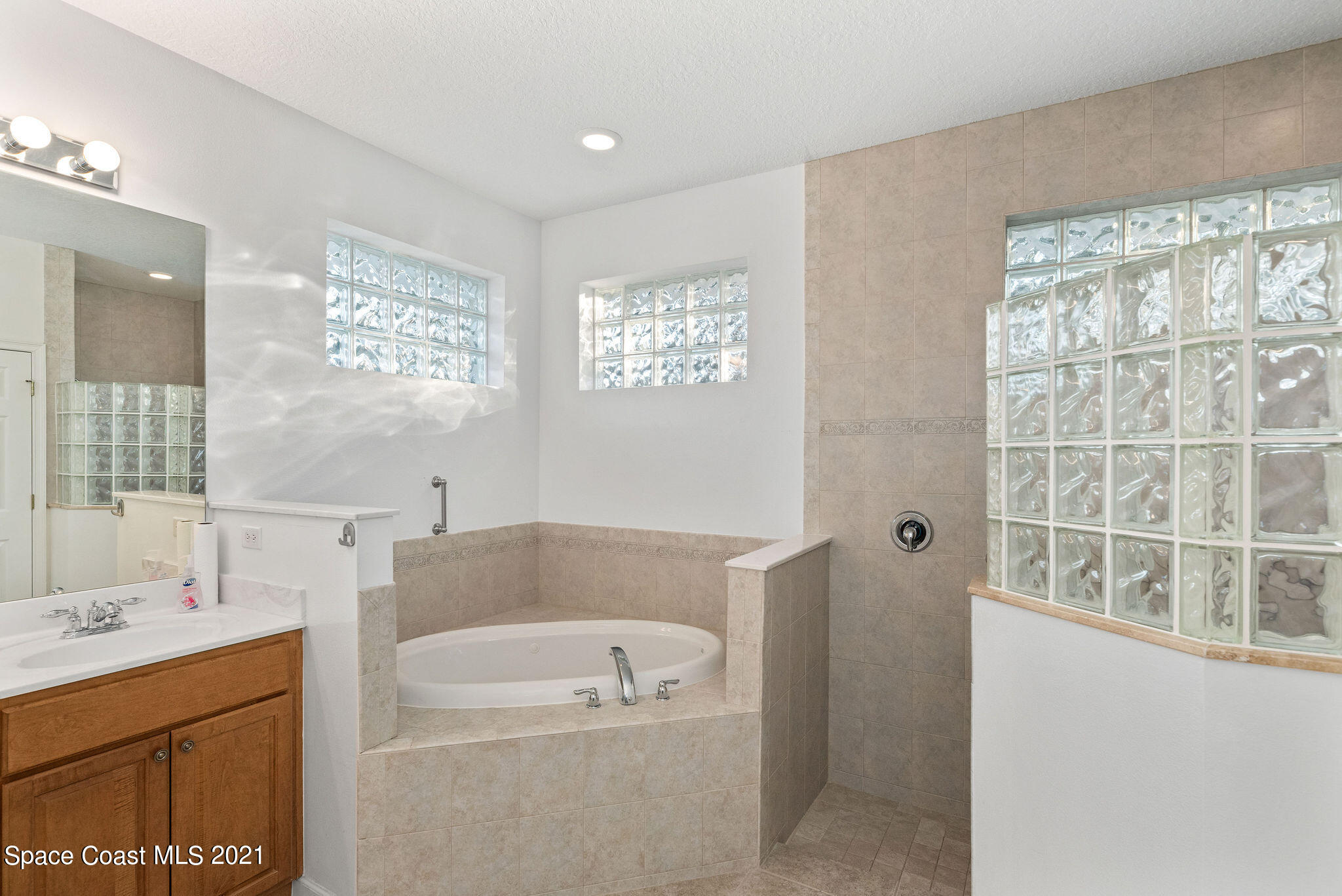 3748 Turtle Mound Road Melbourne, FL 32934 - Photo 29 of 68 a bathroom with a tub a sink and a large mirror