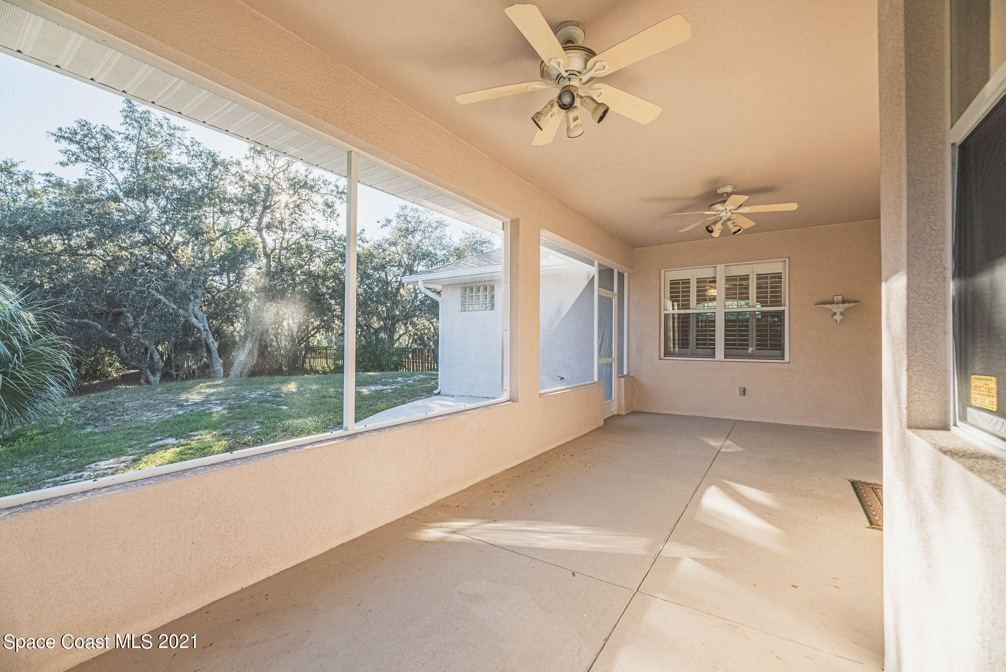 3748 Turtle Mound Road Melbourne, FL 32934 - Photo 35 of 68 a view of a big room with balcony ceiling fan and floor to ceiling window and trees