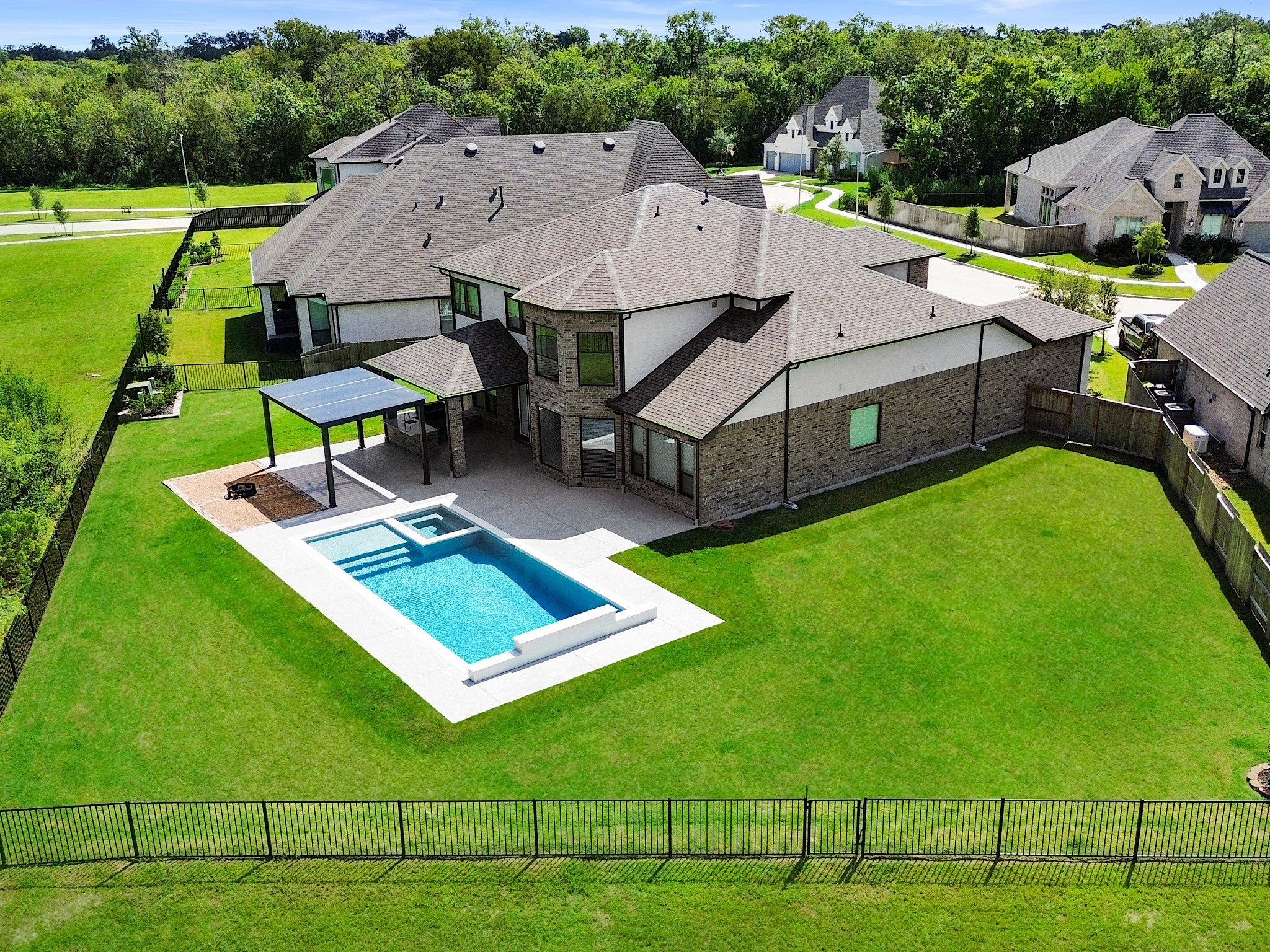 30214 Crossfield Road Fulshear, TX 77441 - Photo 2 of 42 This aerial view reveals a true backyard retreat with a private pool and spa, covered outdoor living, and an expansive fenced lawn.