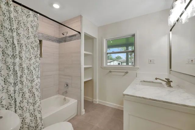 a bathroom with a granite countertop sink a toilet and shower