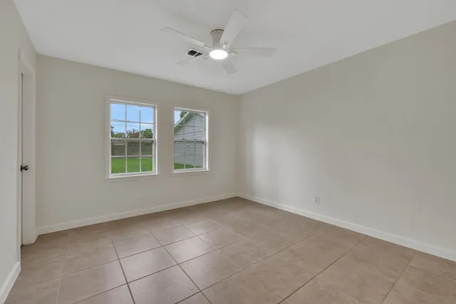 an empty room with windows and ceiling fan