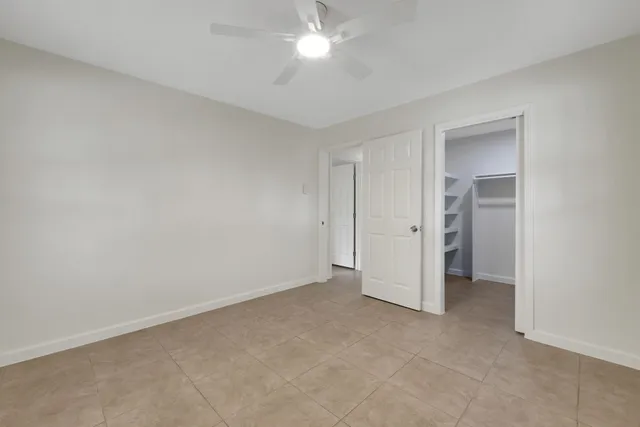 an empty room with closet and a ceiling fan