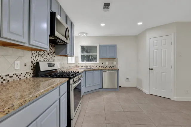 a kitchen with stainless steel appliances granite countertop a stove sink and cabinets