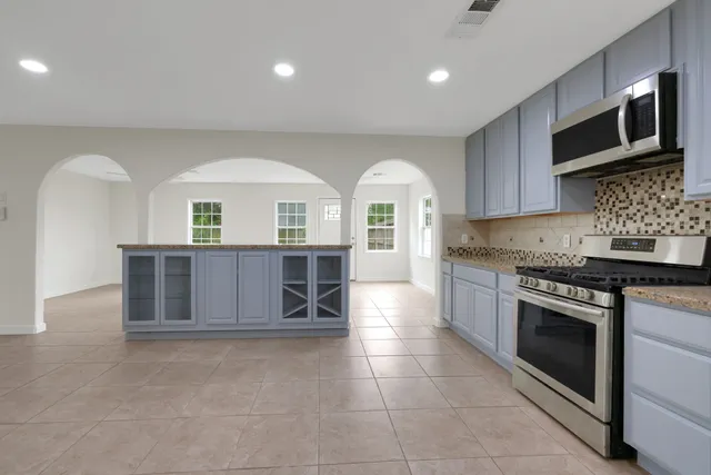 a kitchen with stainless steel appliances granite countertop a stove a sink and a microwave