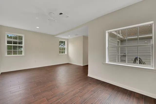 a view of an empty room with wooden floor and windows