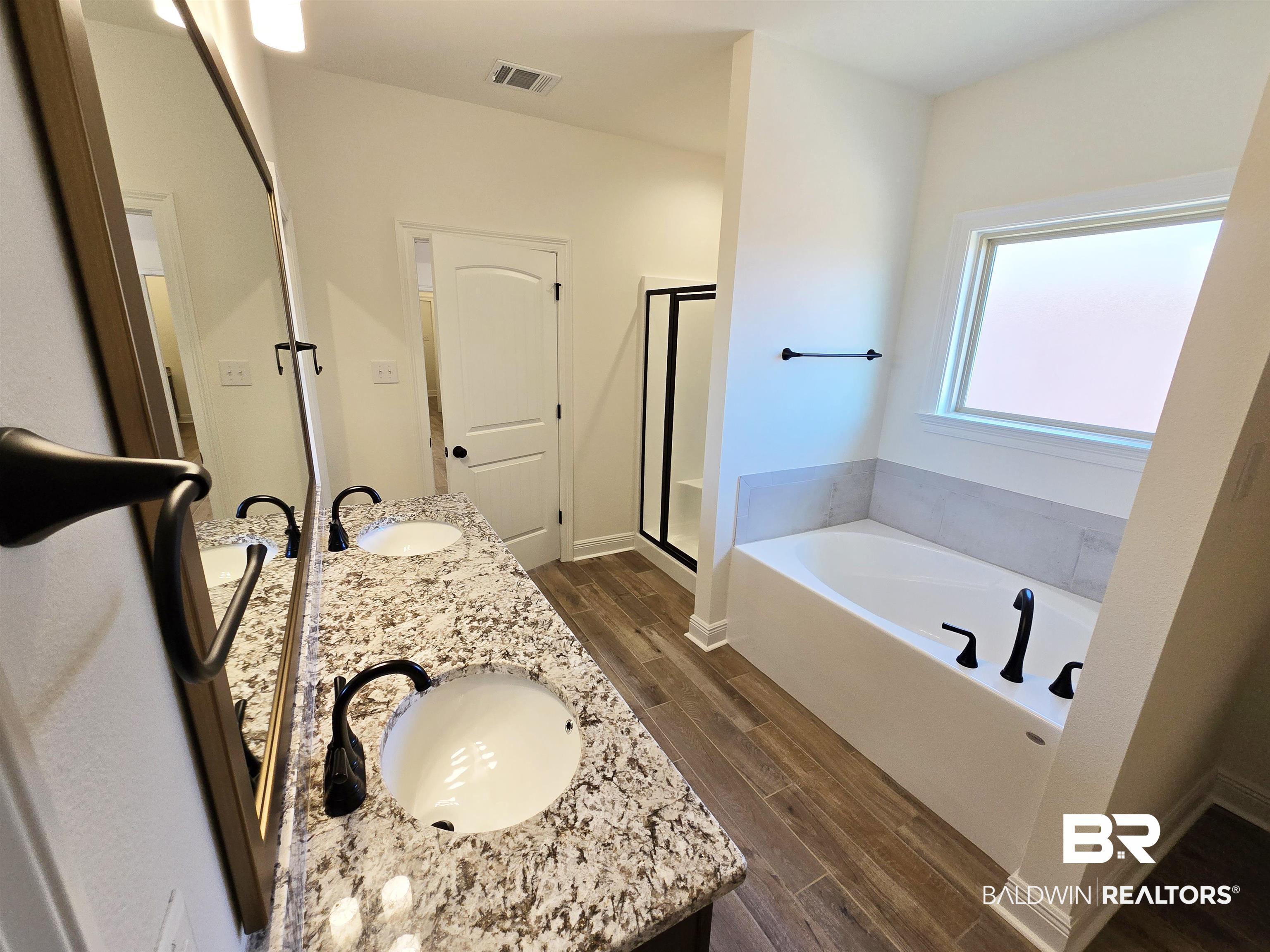 11178 Bonaventure Avenue Daphne, AL 36526 - Photo 12 of 20 Full bathroom featuring double vanity, wood finish floors, a bath, and a shower stall