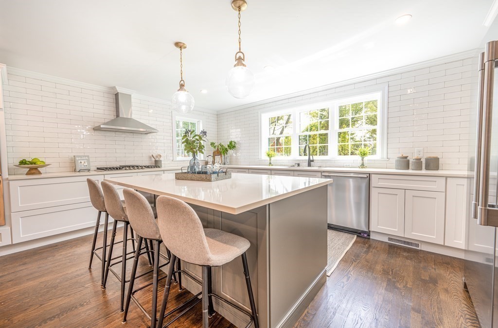 a kitchen with stainless steel appliances a white table chairs and a wooden floor