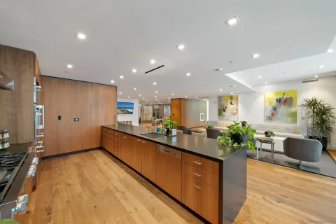 a large kitchen with stainless steel appliances a large counter top a stove and a refrigerator